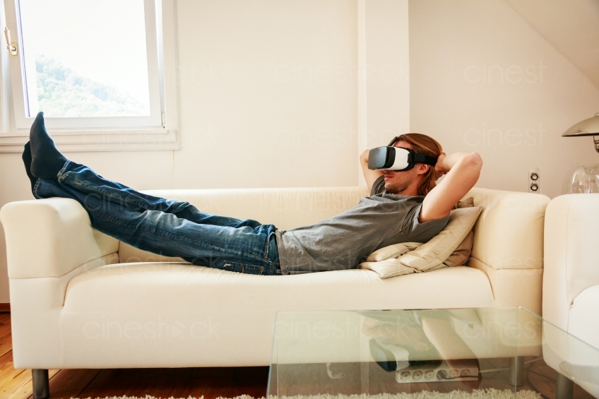Mann liegt mit VR-Brille auf dem Sofa 20160810