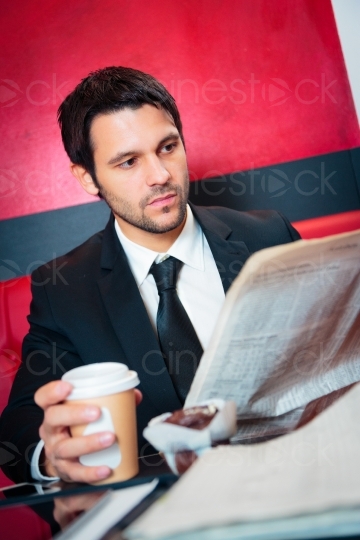 Mann mit Anzug liest Zeitung im Café 20121117-130