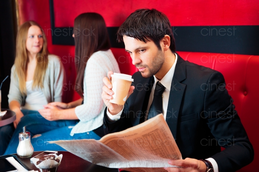 Mann mit Anzug und Kaffee ist in Zeitung vertieft 20121117-125