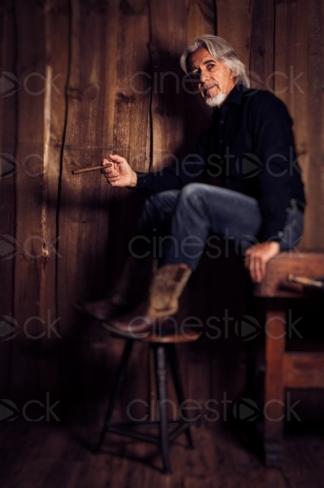 Mann mit Cowboystiefeln und Zigarre sitzt auf Tisch 20160809-0051