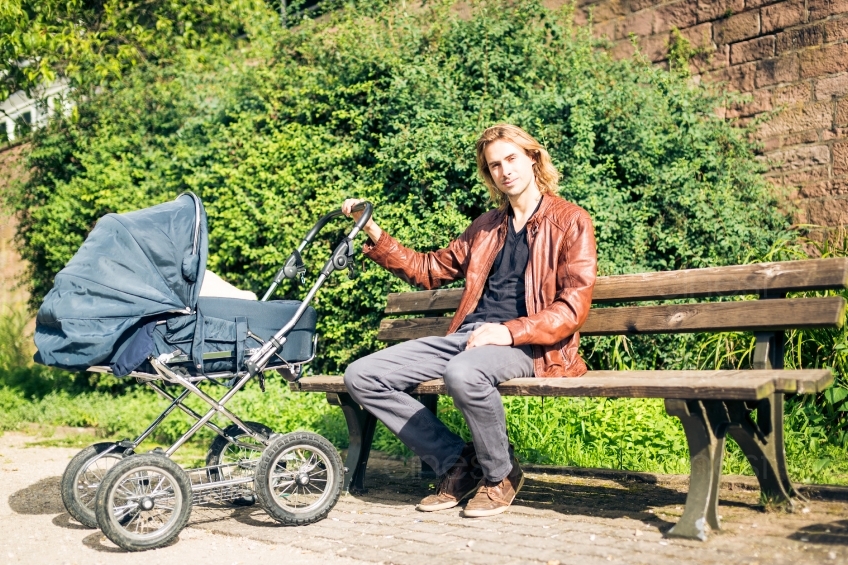 Mann mit Kinderwagen auf Parkbank in der Sonne 20160810-0031