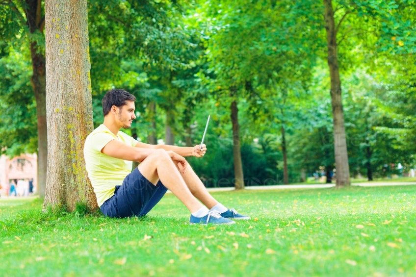 Mann mit Tablet an Baum in Park 20130811-heidel-0839