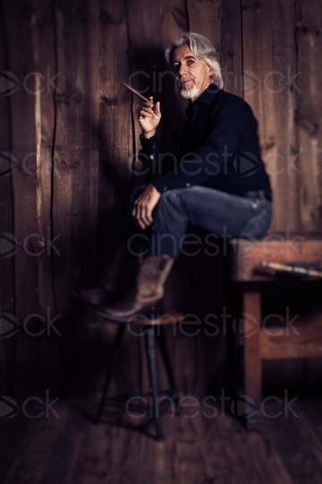 Mann mit Zigarre und Cowboystiefeln mit Hocker 20160809-0048