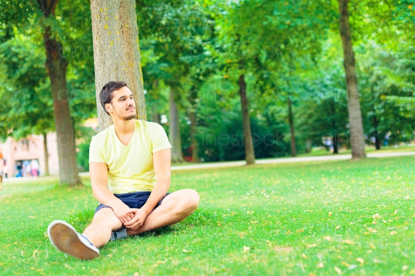 Mann sitzt im Park vor Baum 20130811-heidel-0849