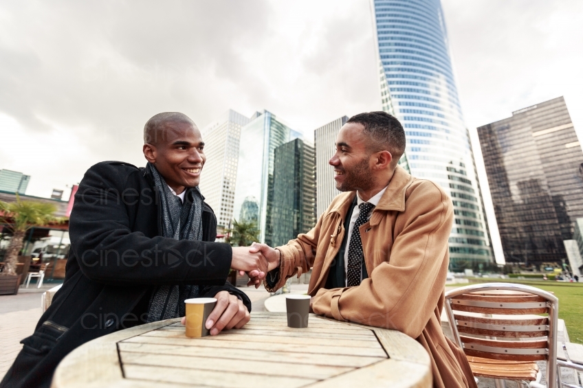 Männer im Anzug und Krawatte trinken Kaffee und schütteln sich die Hände 20160426