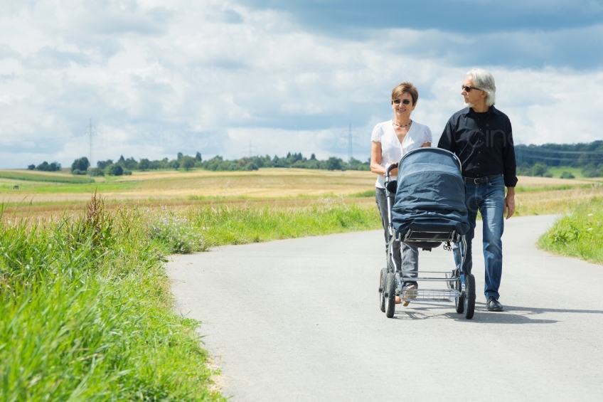 Oma und Opa gehen mit Enkelkind im Kinderwagen spazieren 20160809