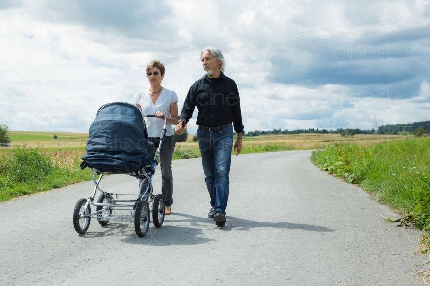 Oma und Opa gehen mit Enkelkind im Kinderwagen spazieren 20160809