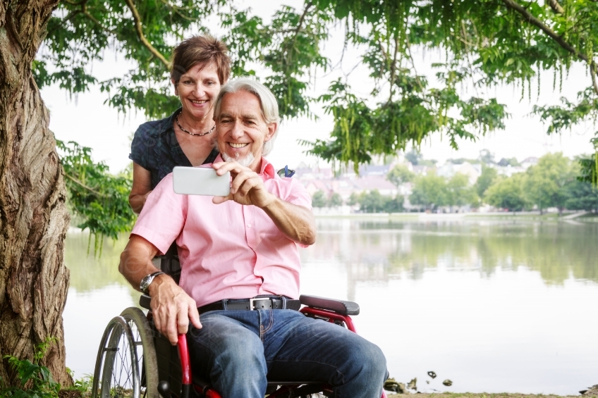 Paar mit Rollstuhl am See macht Selfie 20160725-0148