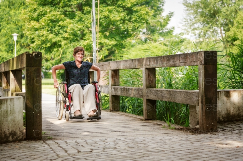 Rollstuhlfahrerin  an Brücke in Park 20160725-0293