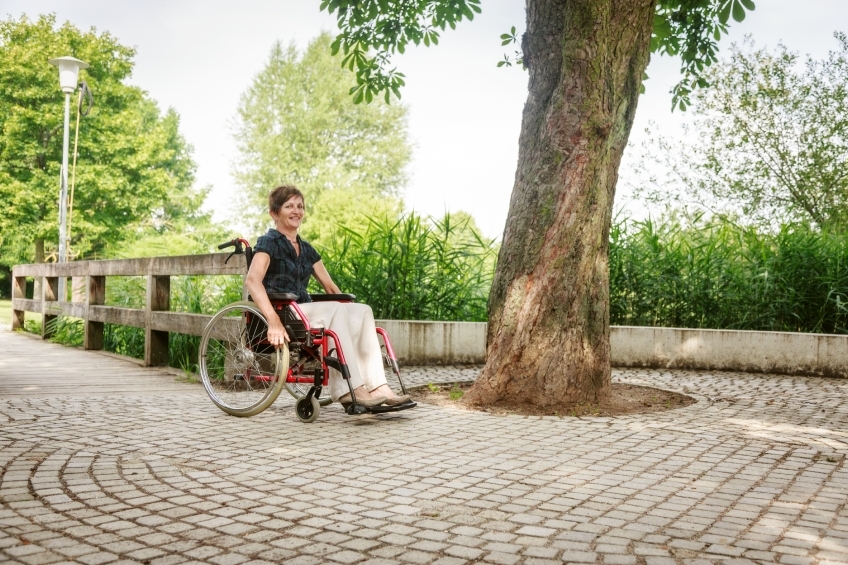 Rollstuhlfahrerin auf Kopfsteinpflaster in Park 20160725-0302