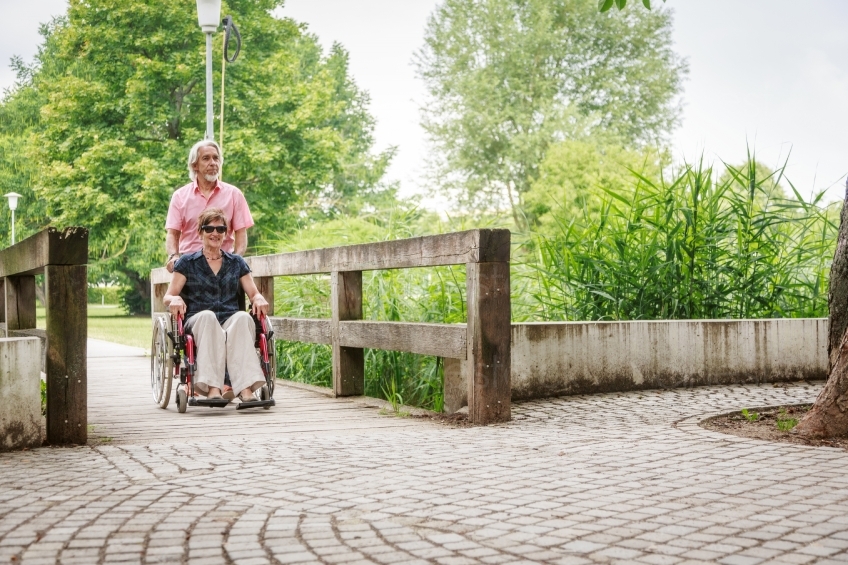 Rollstuhlfahrerin und Mann an Brücke in Park 20160725-0250